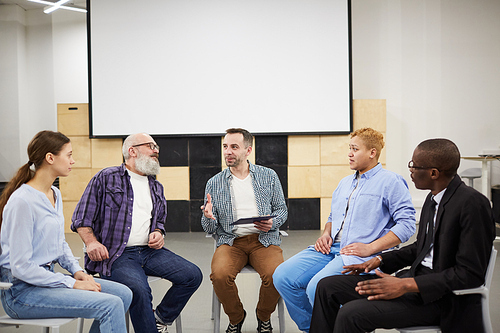 Portrait of mature psychologist leading therapy session in support group, copy space