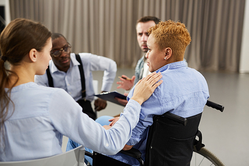 Back view portrait of mixed race woman crying in support group with people comforting her, copy space