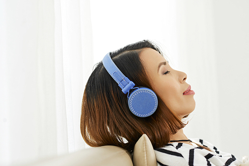 Beautiful relaxed young Asian woman enjoying music in her headphones