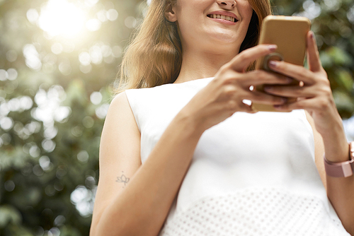 Young woman smiling when texting her friends on sunny day