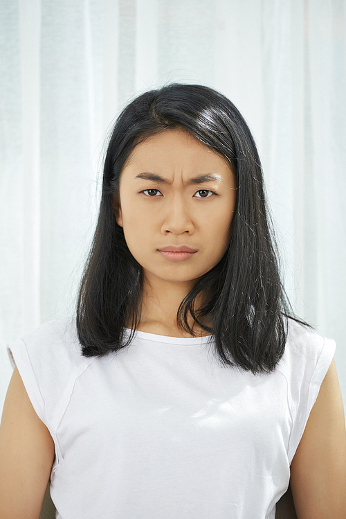 Portrait of unhappy frowning Asian teenage girl 