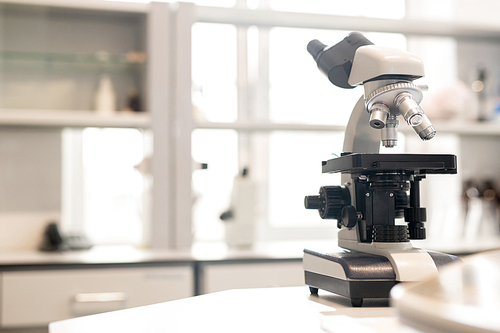 Close-up of modern microscope used for biological and chemical experiments placed on desk in scientific laboratory