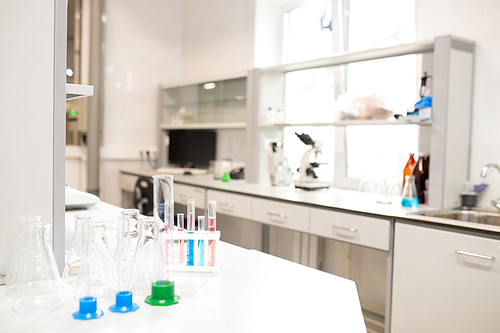 Colorful liquids in test tubes, empty beakers and stands placed on table in university laboratory