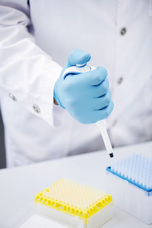 Close-up of unrecognizable laboratory specialist in sterile gloves using modern dropper while adding samples into test tubes