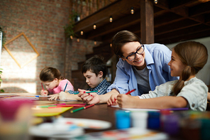 Portrait of smiling young woman working with kids in art class, copy space