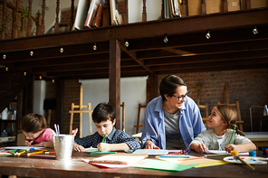 Portrait of happy young woman working with kids drawing pictures in art class, copy space