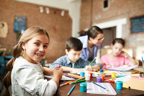 Portrait of cute little girl  while enjoying art class with group of children, copy space