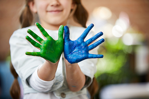 Close up of unrecognizable little girl showing hands colored with paint, finger painting and creativity concept
