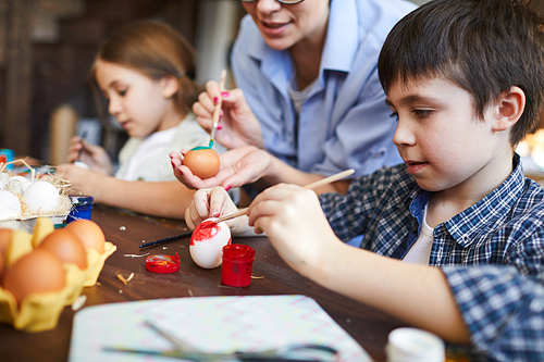 Side view portrait of cute boy painting eggs in art and craft class while preparing for Easter holidays, copy space