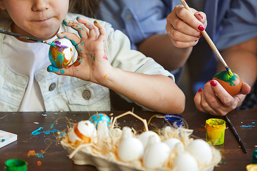 Closeup of cute little girl painting Easter eggs with mother