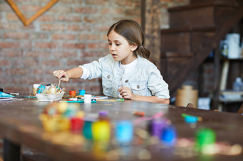 Portrait ofcute little girl making Easter decorations in arty studio, copy space