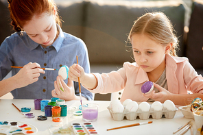 Portrait of two girls hand painting Easter eggs in art class