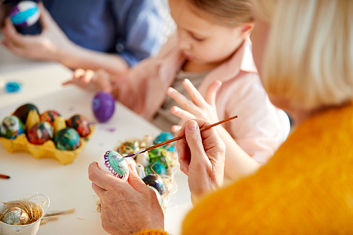 High angle portrait of unrecognizable mature woman painting Easter eggs in art class with children, copy space