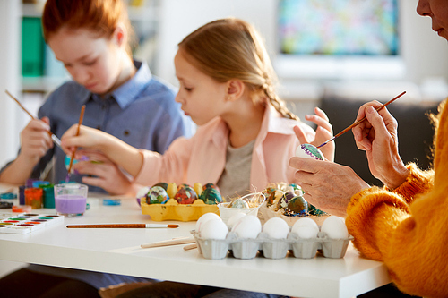 Side view portrait of unrecognizable matter woman painting Easter eggs in art class with children, copy space