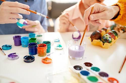 Closeup of family painting eggs for Easter together, copy space