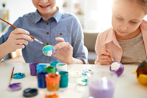 Cropped portrait of two girls painting Easter eggs together in art class