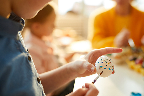 Closeup of unrecognizable child painting eggs for Easter, copy space
