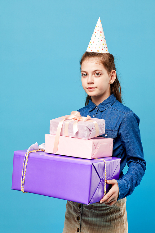 Waist up  portrait of teenage girl holding Birthday presents posing against pastel blue background, party concept