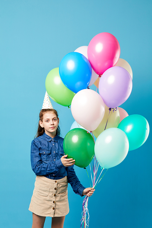 Portrait of teenage girl holding balloons  posing against pastel blue background, Birthday party concept