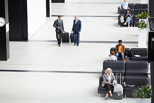 Above view of business employees in suits moving to gates of departure area, other people sitting on sofas