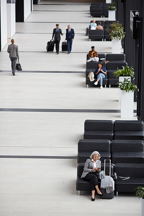 Above view of business people sitting and walking in modern airport waiting room