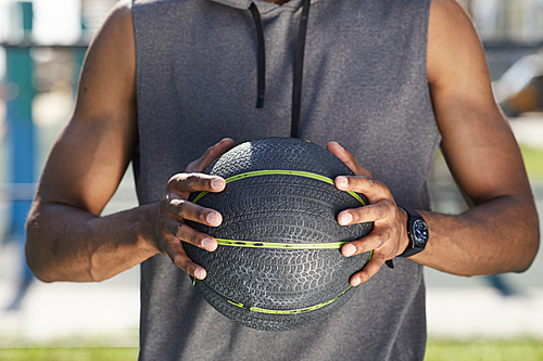 Mid section portrait of muscular African man holding basketball ball outdoors, copy space