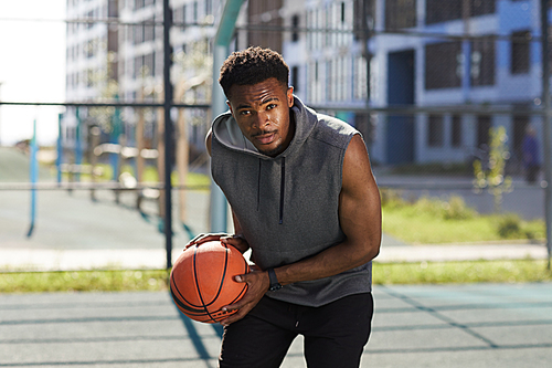 Portrait of determined basketball player rushing at camera holding ball, copy space