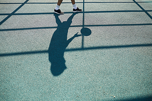 Silhouette of unrecognizable man playing basketball in outdoor court, sports background, copy space
