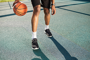Muscular legs of unrecognizable basketball player training in outdoor court, copy space