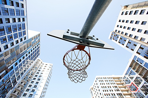 Low angle view at basketball hoop against sky in urban background, copy space
