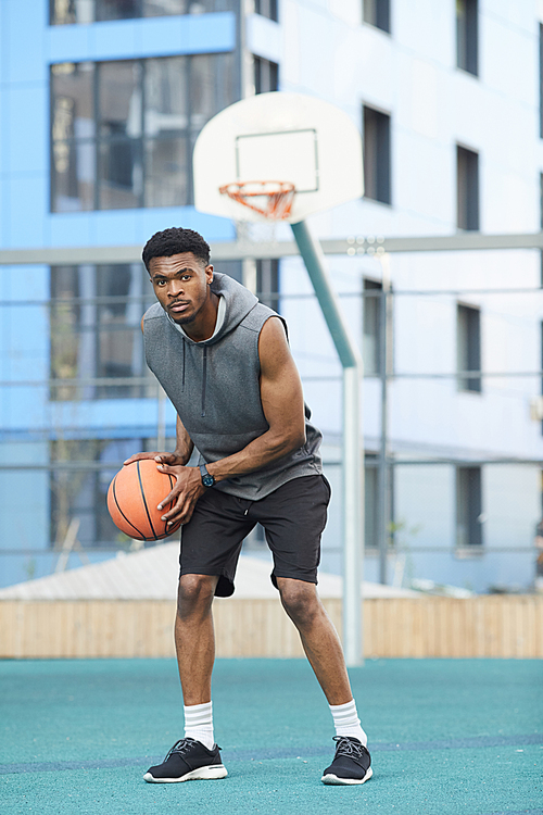 Full length portrait of African basketball player practicing in outdoor court