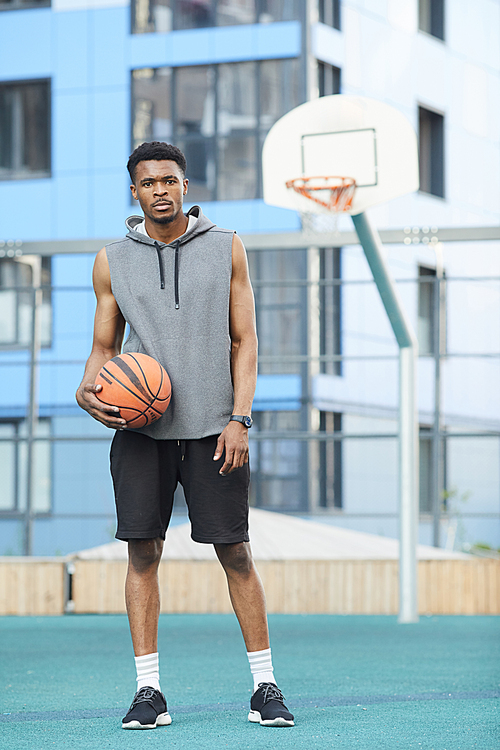 Full length portrait of African basketball player posing in outdoor court