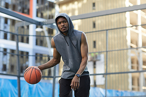 Action portrait of African basketball player practicing in outdoor court, copy space