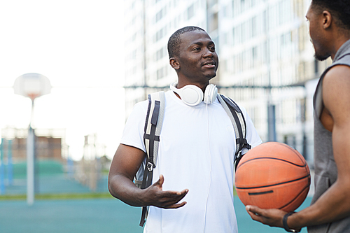 Waist up portrait of two African-American guys chatting on basketball court outdoors, copy space