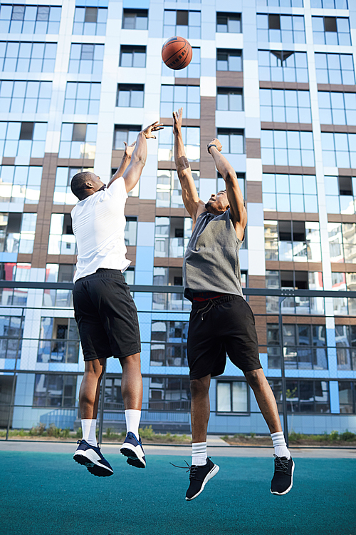 Full length action shot of two muscular African man playing basketball in urban setting