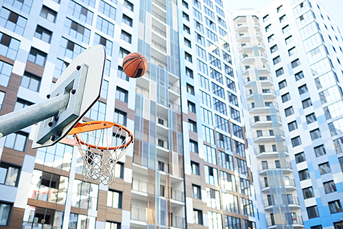Sports background of basketball ball flying through hoop in urban setting, copy space