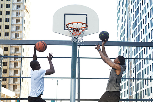 Back view of two sportive African-American men playing basketball in urban setting, copy space
