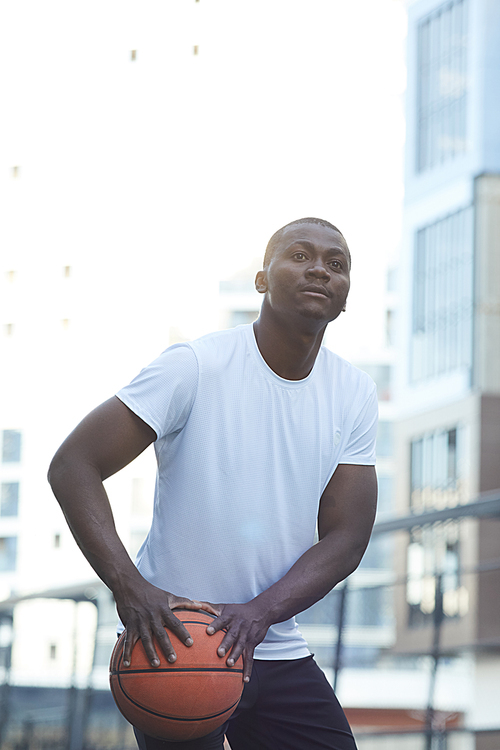 Portrait of muscular African man playing basketball in urban setting