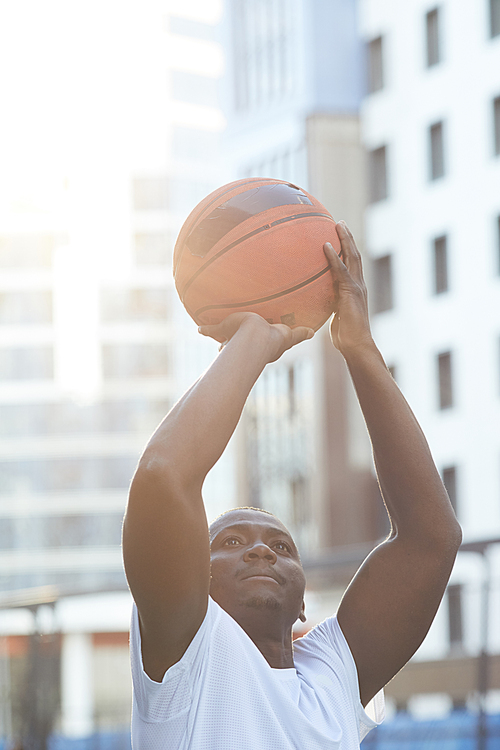 High section portrait of muscular African man throwing basketball ball outdoors, copy space