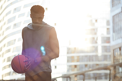 Waist up portrait of sportive African man posing in basketball court outdoors, copy space