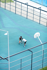 High angle view at two African-American men playing basketball in outdoor court, copy space