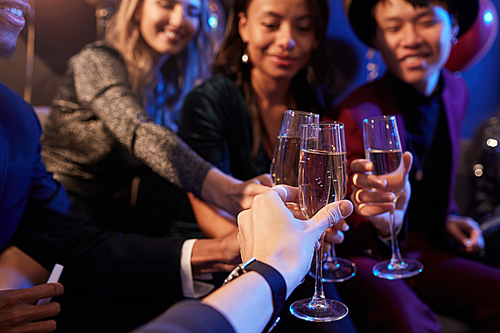Close up of elegant young people clinking champagne glasses while celebrating at party in nightclub, copy space