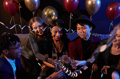 High angle view at multi-ethnic group of trendy young people clinking champagne glasses during party in nightclub