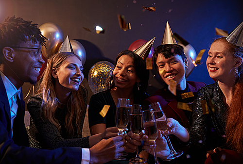 Waist up portrait of elegant young people clinking champagne glasses while celebrating holiday at party in nightclub, copy space