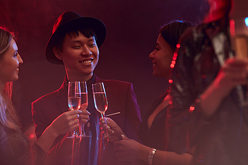 Group of smyoung people drinking champagne in while enjoying party in nightclub or restaurant