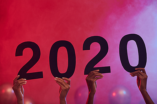 Background image of hands holding 2020 during Christmas party in nightclub, copy space