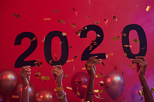 Background image of hands holding 2020 during Christmas party in nightclub with balloons and confetti, copy space