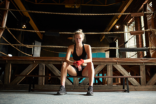 Full length portrait of strong young woman waiting by boxing ring at sports club, copy space