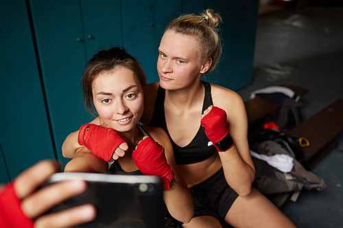 High angle portrait of two female fighters taking selfie in changing room before boxing practice, copy space