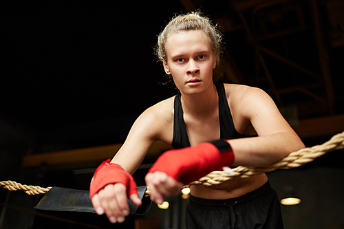 Dramatic portrait of tough female boxer  while standing in boxing ring, copy space